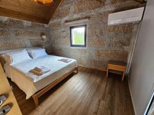 1 dormitorio con cama y pared de ladrillo en Quinta de Casal do Bairro Casa do Alpendre en Guimarães