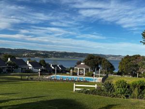 a resort with a swimming pool and a body of water at Blu Belle Lagoon Cottage in Knysna