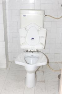 a white toilet in a bathroom with a hose at Perfect Homestay Ujjain in Ujjain