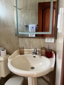 ein Badezimmer mit einem Waschbecken, einem WC und einem Spiegel in der Unterkunft Suite Los Sauces in Ibarra