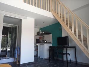 a living room with a staircase and a table with a television at Petite maison avec jardin entre lac et village in Hourtin +29 photos