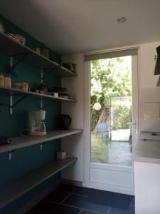 a kitchen with shelves and a door to a patio at Petite maison avec jardin entre lac et village in Hourtin
