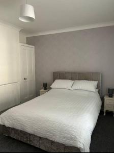 een slaapkamer met een groot bed met witte lakens bij Camisila in Campbeltown