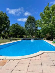 a blue swimming pool with trees in the background at 2 chambres, piscine et calme, Sud Charente in Bardenac
