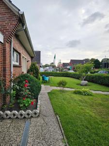 a garden with a house and a yard with flowers at Ferienwohnung Mond&Wasser 2 in Norden