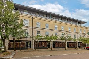 un gran edificio en una calle con árboles delante en MK CITY CENTRE, THE DIAMOND SUITE, FREE Parking Space, PREMIUM SPACIOUS Apartment with FOOSBALL TABLE en Milton Keynes