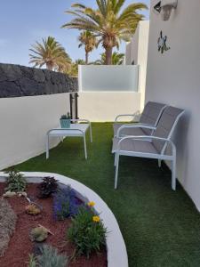 a patio with two chairs and a table and plants at Bungalow Paseo del Mar- PLAYA ROCA Residence sea front access - Free AC - Wifi in Costa Teguise