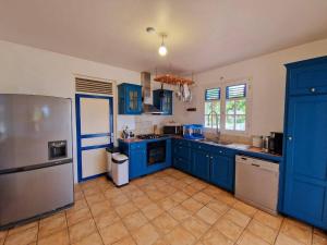 La cuisine est équipée de placards bleus et d'un réfrigérateur en acier inoxydable. dans l'établissement BluePalm case, à Petit-Bourg