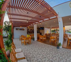 a wooden pergola in a restaurant with tables and chairs at Hotel La Colina in Ica