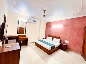 Dormitorio con cama, escritorio y TV en Ashoka International Hotel - Karol Bagh New Delhi en Nueva Delhi