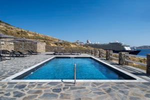 a swimming pool with a cruise ship in the background at Alkistis Beach Hotel - Adults Only in Agios Stefanos