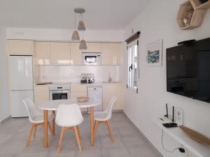 una cocina con mesa y sillas y una cocina con armarios blancos. en Bungalow Paseo del Mar- PLAYA ROCA Residence sea front access - Free AC - Wifi en Costa Teguise