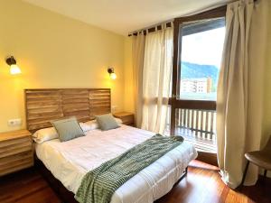 a bedroom with a bed and a large window at Apartament d'estil pirineic amb vistes úniques by RURAL D'ÀNEU in Esterri d'Àneu