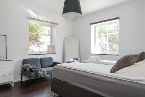 a bedroom with a bed and a chair and two windows at The Rose Valley room in a shared villa in Gothenburg