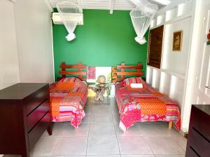 1 Schlafzimmer mit 2 Betten und einer grünen Wand in der Unterkunft Case Coco Pointe Batterie. Piscine, vue mer, 4 p. in Deshaies
