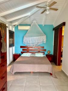 Schlafzimmer mit einem Bett und einem Deckenventilator in der Unterkunft Case Coco Pointe Batterie. Piscine, vue mer, 4 p. in Deshaies