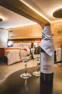 2 verres à vin assis sur une table avec une bouteille de vin dans l'établissement Altipacha Ayacucho Hotel, à Ayacucho