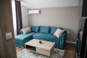 uma sala de estar com um sofá azul e uma mesa de centro em NOMAD Apartments em Niš