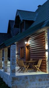 due sedie e un tavolo sul portico di una baita di tronchi di Mountain Haven Deluxe a Žabljak