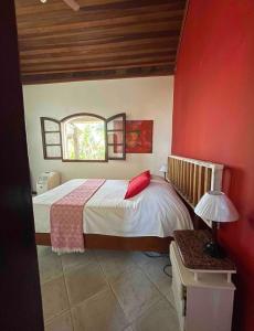 ein Schlafzimmer mit einem Bett mit einer roten Wand in der Unterkunft Casa Flamboyant Buzios in Búzios