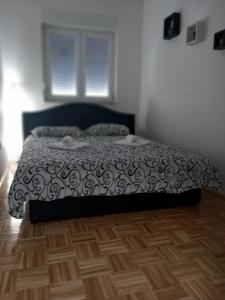 a bedroom with a bed with a black and white comforter at Apartman IRIS in Bijeljina