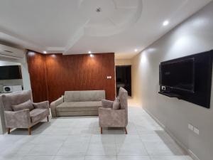 - un salon avec deux chaises et une télévision à écran plat dans l'établissement عنوانك للشقق المخدومة, à Abha