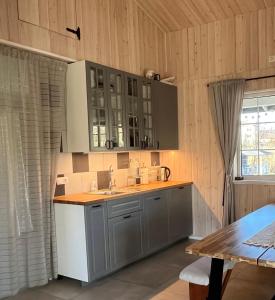 a kitchen with gray cabinets and a sink and a table at Pirties namelis Paliekys in Lekėčiai +11 photos