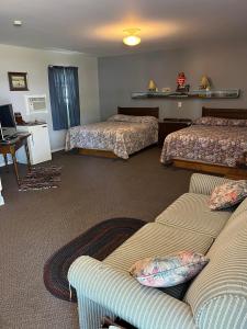 Habitación de hotel con 2 camas y sofá en Bluebird Motel en Claresholm
