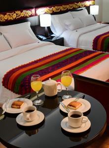 Altipacha Ayacucho Hotel في اياكوتشو: غرفة مع سرير مع طاولة مع كأسين من النبيذ