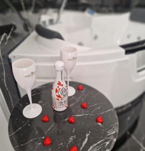 twee wijnglazen en een fles op een tafel met rode harten bij Black and White 17 in Barletta