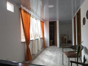 un soggiorno con tende arancioni, tavolo e sedie di Mi casa tu casa a Santa Rosa de Cabal