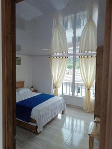 a bedroom with a bed and a large window at Mi casa tu casa in Santa Rosa de Cabal