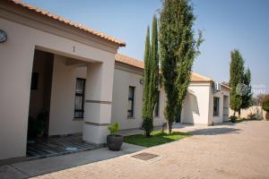 a house with a garage and two trees in front at Kendi's Inn Self Catering Apartments in Jwaneng