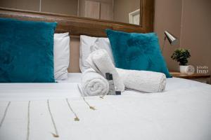 a white bed with towels and pillows on it at Kendi's Inn Self Catering Apartments in Jwaneng