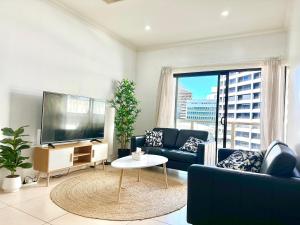 a living room with a tv and a couch and a table at Bundled Bliss 2 bedroom Condo in Adelaide CBD in Adelaide