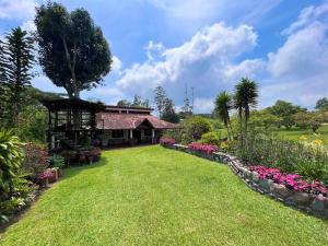 a garden with a house and some flowers at Cabaña amplia con piscina, naturaleza y cercana in Los Santos