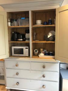a white dresser with a microwave on top of it at Orchard house guest studio accommodation in Marchwiel