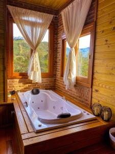 uma grande banheira num quarto com janelas em Chalé Vale das Pedras em Praia Grande