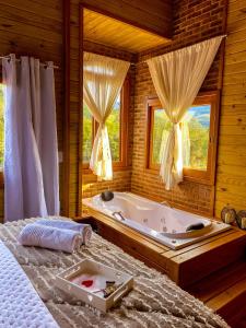 um quarto com uma banheira e uma cama em Chalé Vale das Pedras em Praia Grande