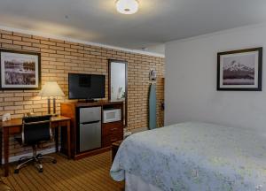 a hotel room with a bed and a desk and a television at Sweet Home Inn in Sweet Home