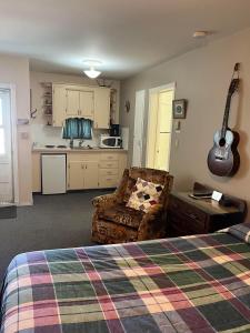 ein Schlafzimmer mit einem Bett und einer Gitarre an der Wand in der Unterkunft Bluebird Motel in Claresholm