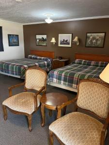 a hotel room with two beds and chairs at Bluebird Motel in Claresholm