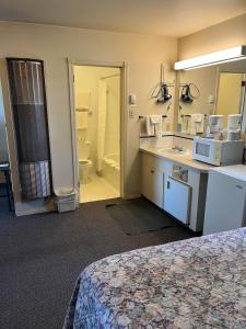 a hotel room with a bed and a bathroom at Bluebird Motel in Claresholm