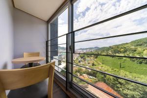 a room with a large window with a chair and a table at Hotel Hue in Tongyeong