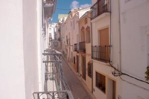 a narrow alley with white buildings and a balcony at Hotel Tàrbena in Tárbena