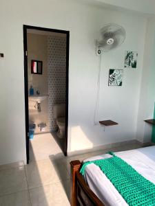 a bedroom with a bed and a bathroom with a fan at Casa Guiwa Hostel in Palomino