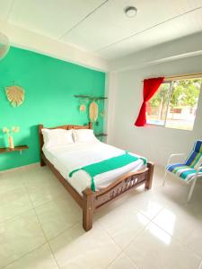 1 dormitorio con cama y pared verde en Casa Guiwa Hostel, en Palomino