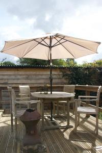 a table and chairs with an umbrella on a deck at Balcarres, Rodborough Avenue in Stroud