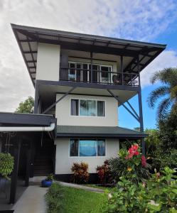 a white house with a balcony and plants at Island Goode's - Luxury Adult Only Accommodation near Hilo in Papaikou