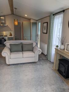 a living room with a white couch and a fireplace at Waterfoot Lodge in Little Habton